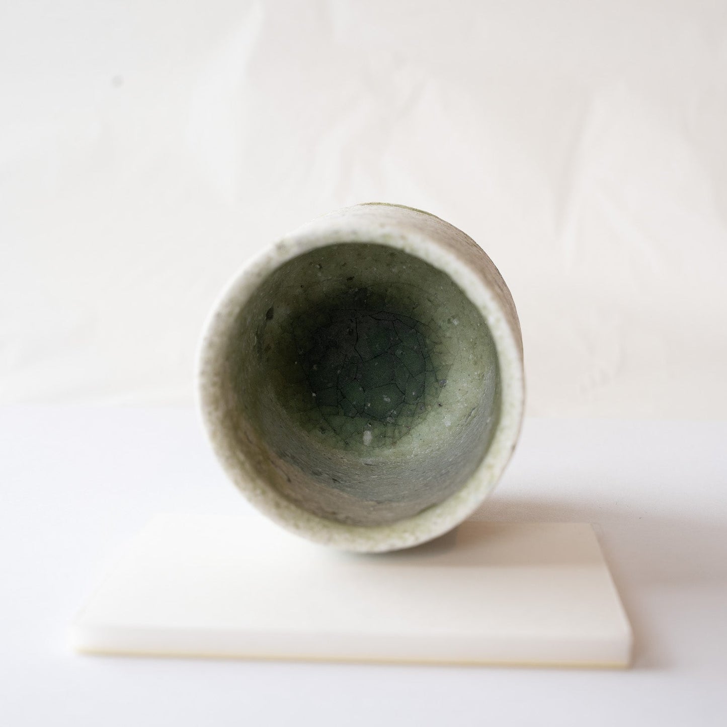 Top-down view into the interior, revealing a deep, clear pool of emerald green glass with delicate crackle patterns at the bottom.
